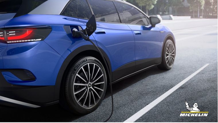 SUV elettrico in ricarica presso una stazione, equipaggiato con pneumatici Michelin progettati per veicoli elettrici.