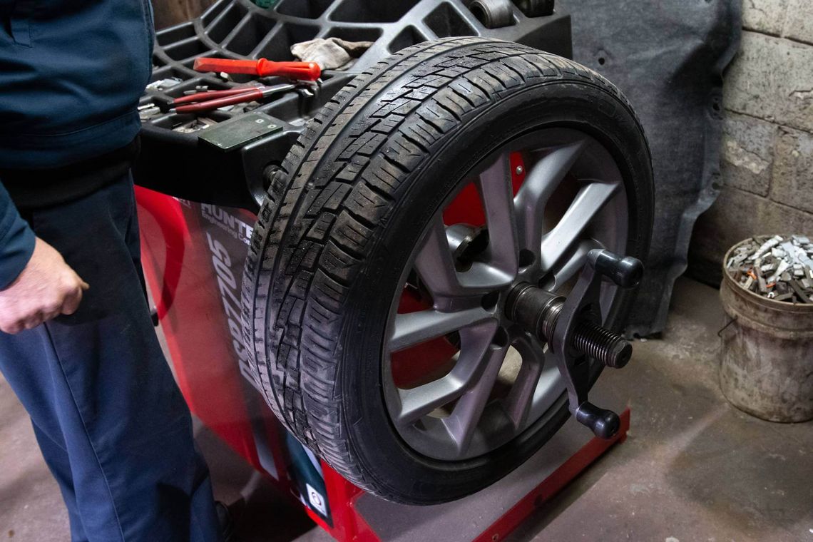 Ruota dell’auto montata su una macchina equilibratrice in officina, con attrezzi e contrappesi visibili nelle vicinanze